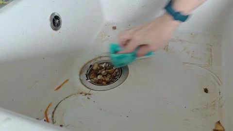 Hand scrubs a dirty kitchen sink with a sponge during cleaning Stock Footage 343165900