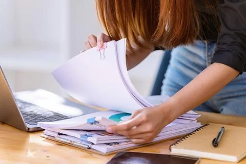 Hand of searching in Stacks of paper documents on wooden desks at the workpla Stock Photos