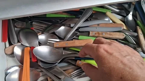 Hand searching through messy kitchen drawer filled with metal cutlery video Stock Footage 339248997