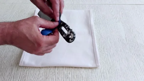 Hand Secures Blue Clamp on Black Tool Over White Cloth Surface Stock-Footage 314492316