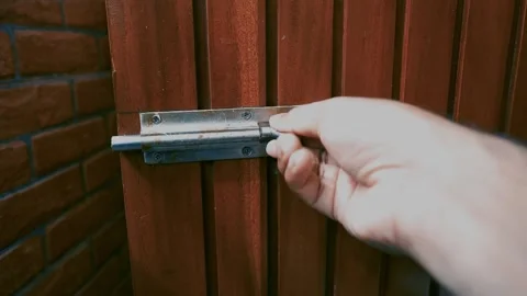 Hand Securing Bolt Lock on Wooden Door, Hand sliding bolt lock on wooden door Stock Footage 317131599
