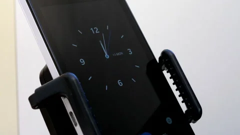 Hand securing mobile phone in holder then swiping screen to show clock. Stock Footage 163230069