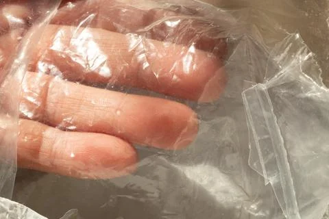 A hand is seen through a clear plastic bag, a close-up of the packaging pla.. Stock Photos