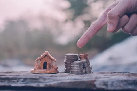 Hand select coins stack home model on wood table Stock Photos