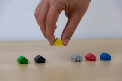 Hand select home, concept different colored game pieces Stockfoto's