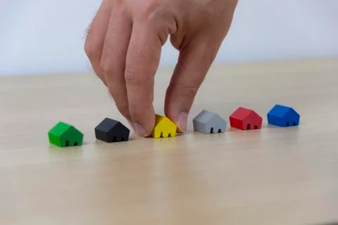 Hand select home, concept different colored game pieces Stockfoto's