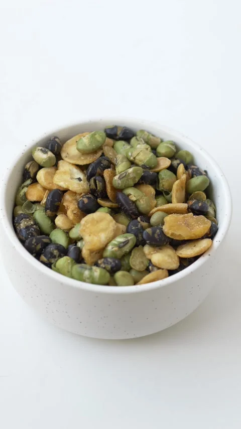 Hand selecting bean snack from bowl of mixed legumes rich in protein and dietary Stock-Footage 331010256