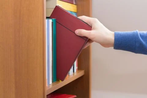 Hand selecting book from bookcase Stock Photos