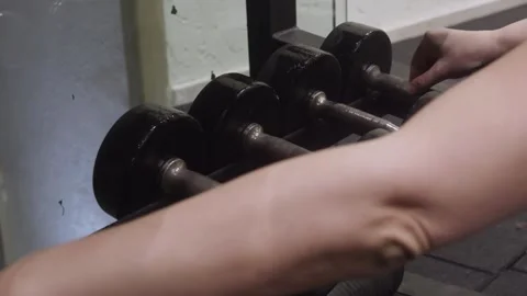 Hand selecting dumbbell from rack in gym Stock Footage 325603626