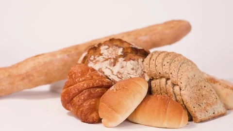 Hand Selecting Fresh Bread from Assorted Bakery Display on White Background Stock Footage 337519100