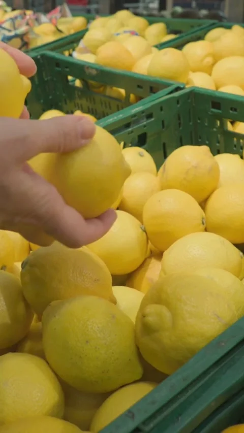 Hand selecting fresh yellow lemons from supermarket crate Video stock 334183315