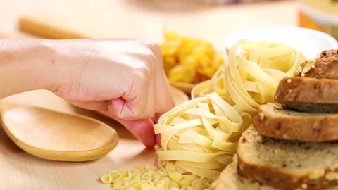 Hand selecting grains and pasta from wooden spoons on a table with bread sl.. Stock Footage 333757160