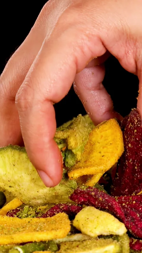 Hand Selecting Mixed Dried Vegetable Chips Against Black Background Stock Footage 320163418