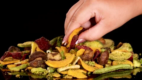 Hand Selecting Mixed Vegetable Chips from Pile on Black Background Stock Footage 315419811