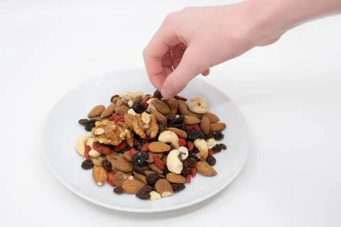 Hand selecting from a plate of mixed fruit and nuts Stock Photos