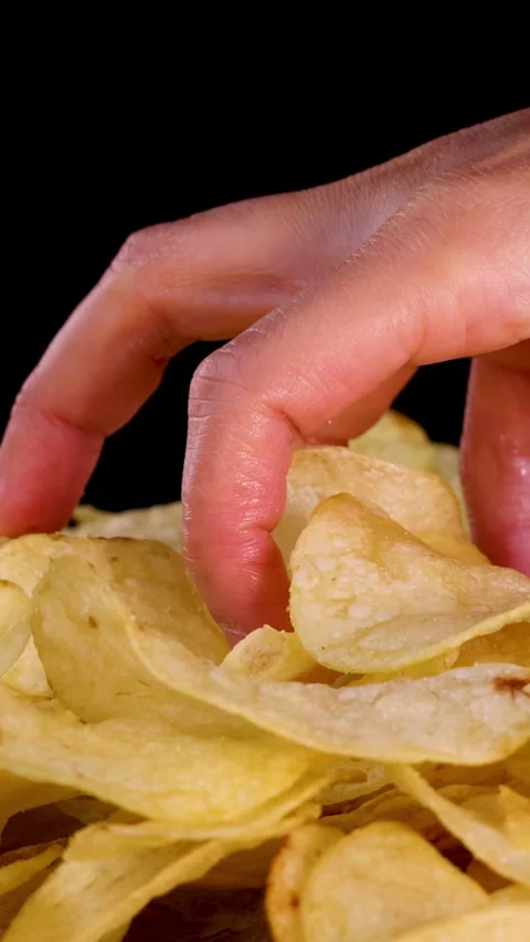 Hand Selecting Potato Chips from Pile on Black Background Stock Footage 318645477
