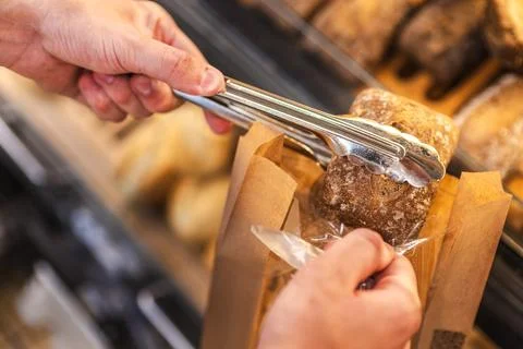 Hand Selecting Rustic Bread Loaf at Bakery Display Stock Photos
