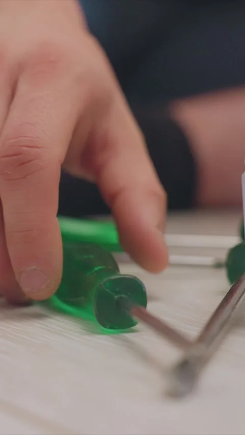 Hand Selecting Screwdriver from Tool Set on Wooden Surface featuring green Stock Footage 346786912