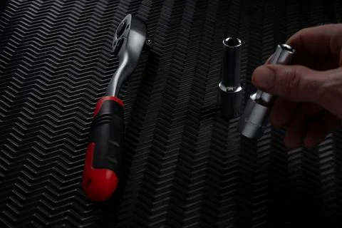 Hand selecting socket attachment next to ratchet wrench on dark textured ba.. Stock Photos