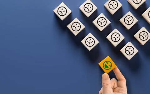 Hand selects orange cube with positive person among many cubes with sad fac.. Stock Photos