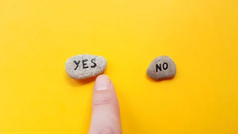 Hand selects a stone no between two pebbles with the text YES and NO Stock Footage 162950207
