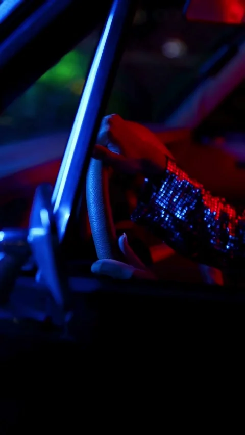 Hand in sequined sleeve holding steering wheel at night 库存影片 331771908