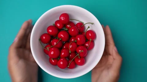 Hand Serving A Bowl of Cherries in Isolated Blue Background 库存影片 267056344