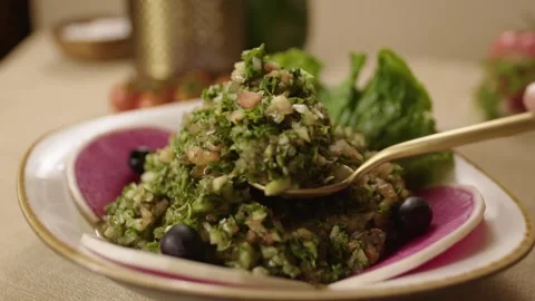 Hand Serving Fresh Turkish Salad with Greens and Olives on Rustic Table Setting Stock Footage 345217961