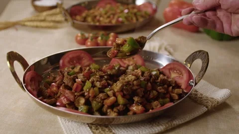 Hand Serving Turkish Sauteed Meat and Vegetables in Traditional Metal Dish on Stock Footage 345277332