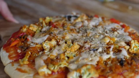 Hand serving vegan pizza with vegetables and vegan cheese on the wooden table Stock Footage 146784099