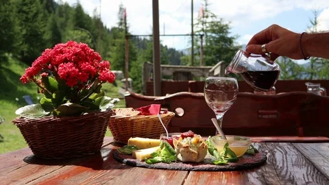 Hand serving wine near cheese plate in tipical lunch in mountain Stock Footage 97409606