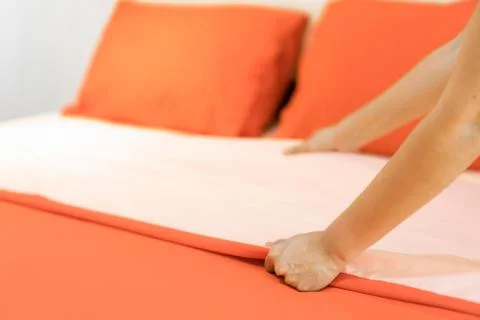 Hand set up white bed sheet in room hotel. Stock Photos