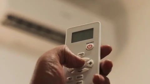 Hand sets the air conditioner temperature with a remote control in a bedroom Stock Footage 344236863