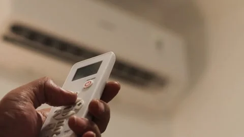 Hand sets the air conditioner temperature with a remote control in a bedroom Stock Footage 344236866