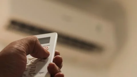 Hand sets the air conditioner temperature with a remote control in a bedroom Stock Footage 344236878