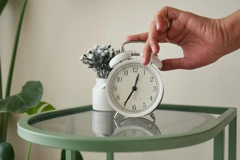Hand sets alarm clock on green table Stock Photos