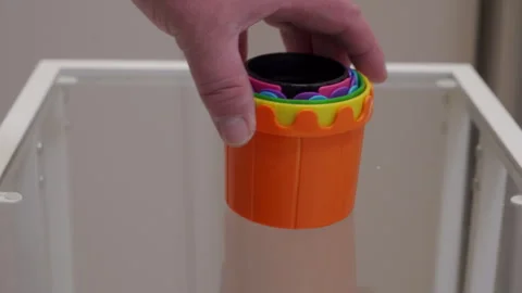 Hand Sets Bright Plastic Stacking Cups Gently on Glass Table with a Soft Thud Stock Footage 321346267