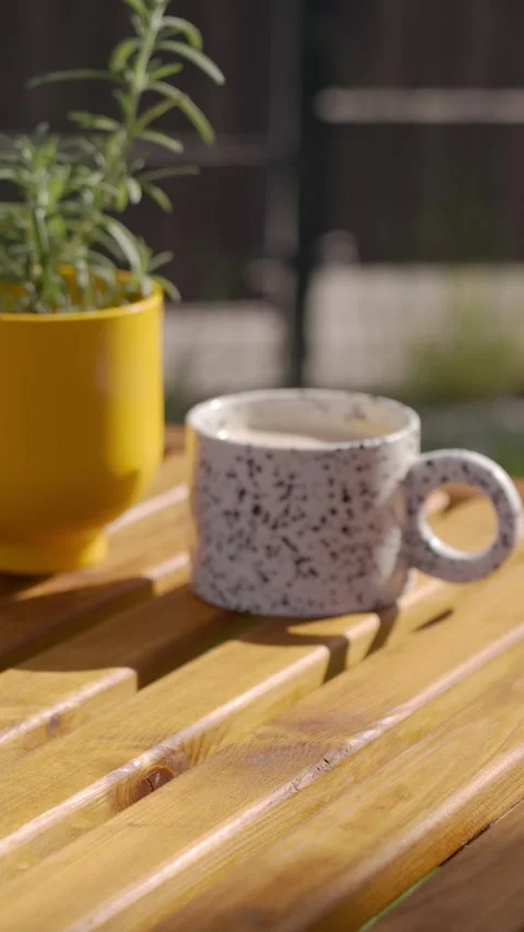 Hand sets cup and plate of bruschetta on sunlit wooden table Stock Footage 342565789
