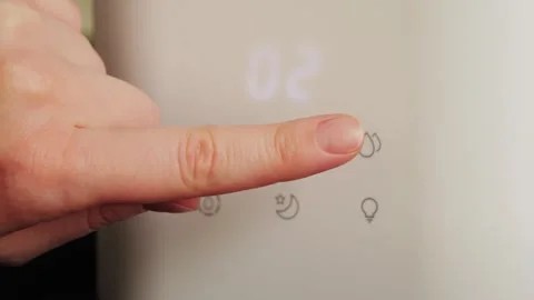 A hand sets the humidity level on a humidifier at home. A modern humidifier that Stock Footage 331798951