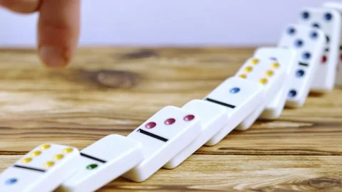 Hand Setting Off a Chain Reaction of Falling Dominoes on a Wooden Table Stock Footage 270514795
