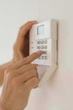 Hand setting code on burglar alarm Stock Photos