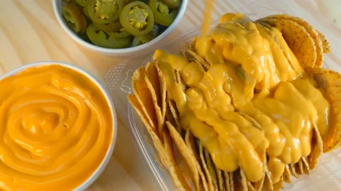 A Hand Setting Down A Bowl Of Nacho Cheese, Jalapeños and Nachos Video stock 220303864