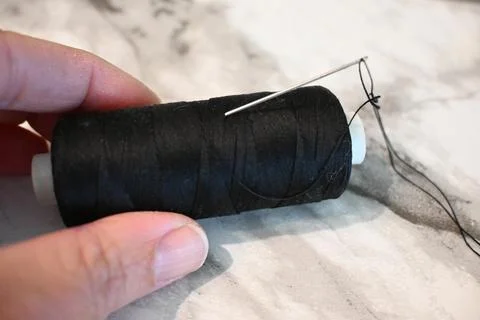 Hand sewing with black thread and needle Stock-Fotos