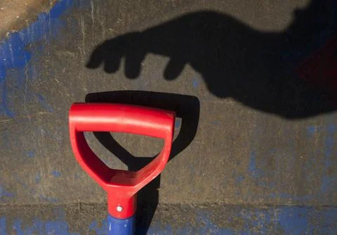 Hand shadow reaching towards red shovel handle, Finland Photos
