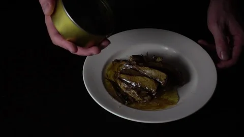A hand shakes sprats from a tin can. Slow mo Stock Footage 74237930