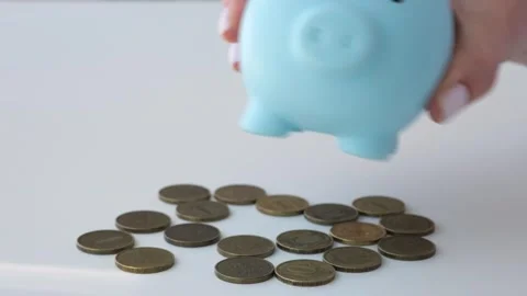Hand shaking empty piggy bank above white desk and lay it on coins upside down Video stock 284413407