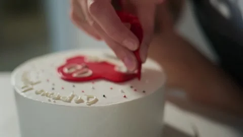 Hand shaping red icing on cake Stock Footage 336094995