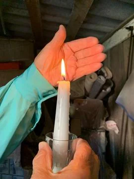Hand shielding burning candle flame Stock Photos