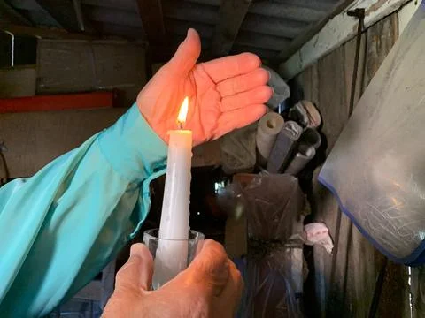 Hand shielding burning candle flame Stock Photos