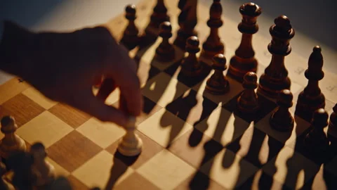 Hand shifting chess pawn on board surface with shadows. Opponent moving item Stock Footage 332338134